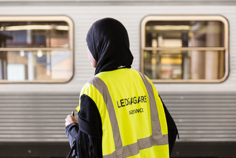 Ledsagaren har en gul reflexväst där det står ledsagare på framsidan och baksidan